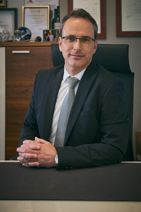 צילום תדמית עסקית של איש עסקים בחליפה עם ידיים שלובות ליד שולחן — אולפן צילום תדמית תל אביב