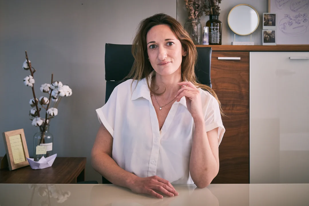 צילום תדמית של אשת עסקים בחולצה לבנה יושבת ליד שולחן עבודה — אולפן צילום תדמית תל אביב